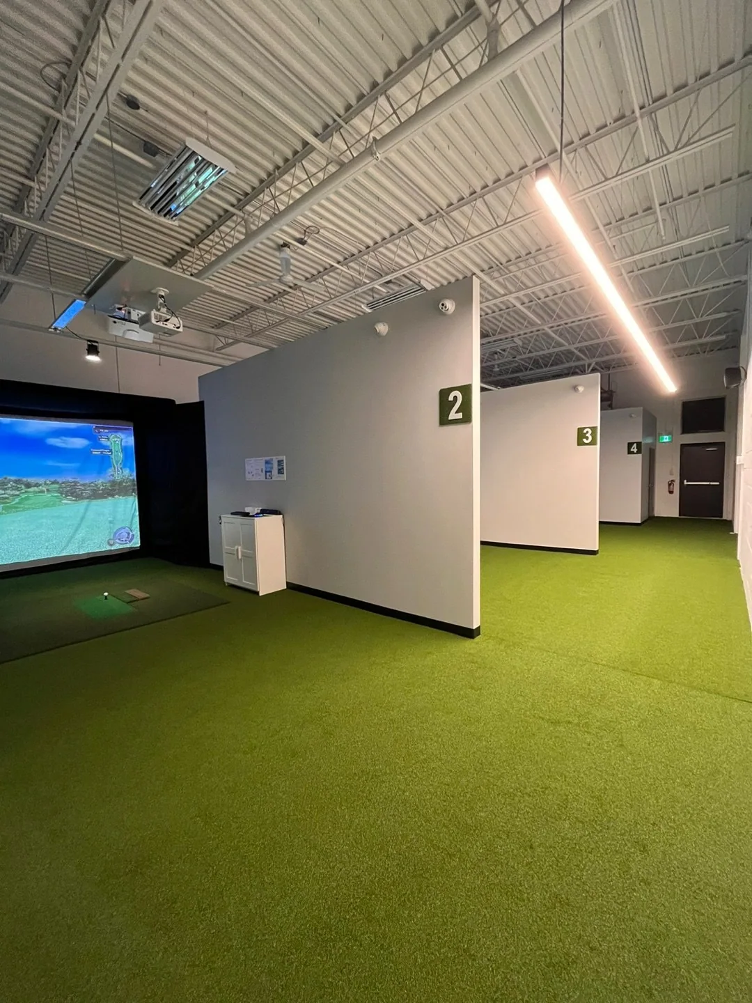 Divided simulator bays with overhead equipment and a shared walkway