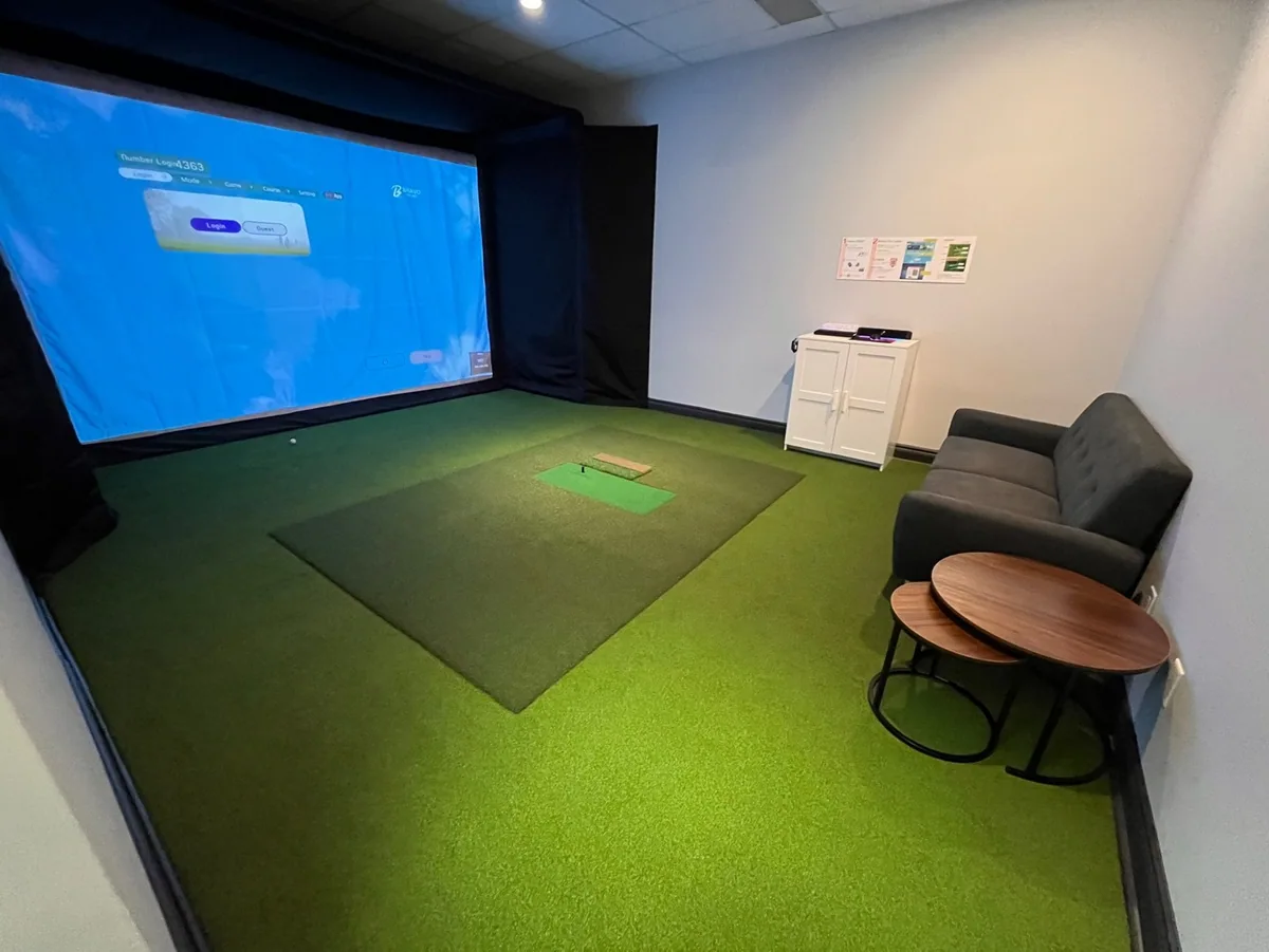 A private simulator room with lounge seating and a side table